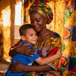 Mère africaine tenant son enfant autiste dans ses bras avec des tissus traditionnels colorés en arrière-plan