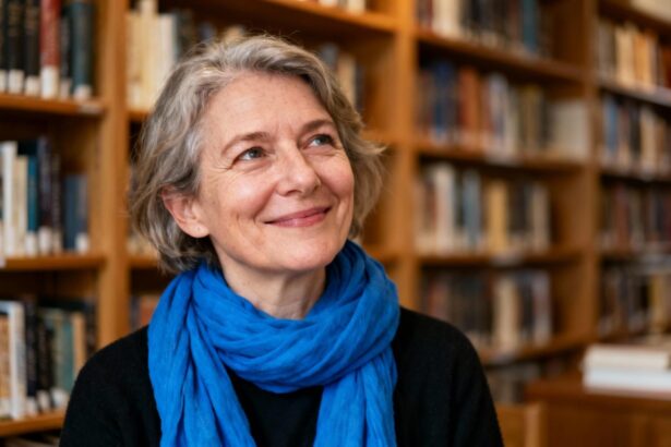 Femme d'âge mûr souriante avec un foulard bleu vif, assise dans une bibliothèque avec des étagères de livres en arrière-plan
