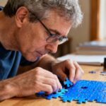 Homme d’âge mûr avec syndrome d’Asperger concentré sur un puzzle coloré dans une pièce baignée de lumière naturelle